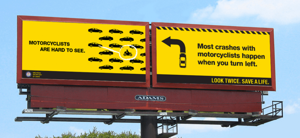 Two billboards side-by-side. The left board shows several illustrated cars with a single motorcyclist. The text reads, "Motorcyclists are hard to see." The right board reads, "Most crashes with motorcyclists happen when you turn left. Look twice. Save a life."